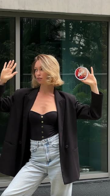 Mulher de blazer segurando um pote Gulo na cidade